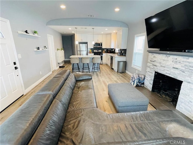 living room with light wood-style floors, a fireplace, baseboards, and recessed lighting