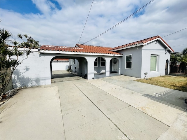 mediterranean / spanish house with fence, driveway, a tiled roof, and stucco siding