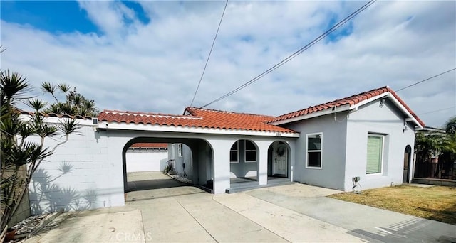 mediterranean / spanish-style house featuring a porch, fence, a tile roof, driveway, and stucco siding