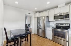 kitchen with white cabinetry, appliances with stainless steel finishes, and light hardwood / wood-style flooring