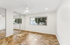 unfurnished bedroom with parquet floors and multiple closets