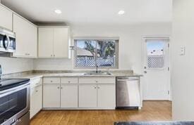 kitchen with sink, stainless steel appliances, white cabinets, and light wood-type flooring