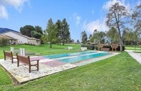 view of swimming pool featuring a yard