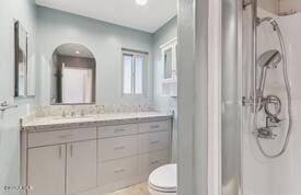 bathroom with walk in shower, vanity, and toilet