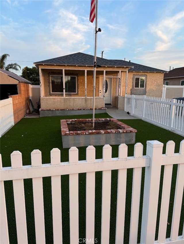 view of front of house featuring roof with shingles, a fenced front yard, and a front yard