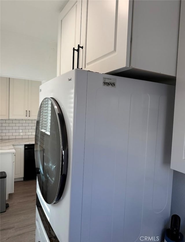 laundry area featuring washer / dryer, light wood-style flooring, and cabinet space