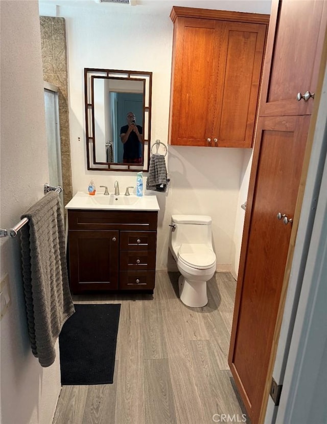 full bath featuring toilet, wood finished floors, visible vents, vanity, and a shower with door