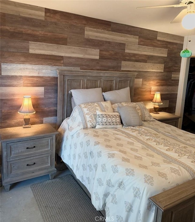 bedroom featuring ceiling fan and wooden walls