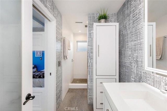 bathroom with walk in shower, wood-type flooring, tile walls, vanity, and decorative backsplash