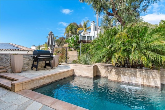 view of swimming pool featuring a patio, pool water feature, and area for grilling