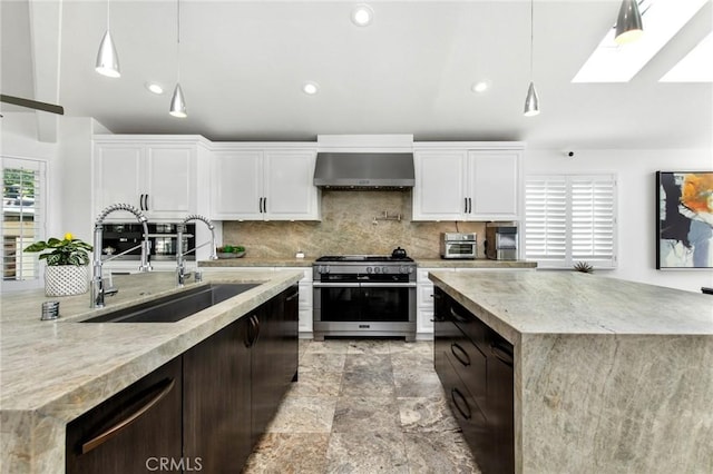 kitchen featuring white cabinetry, double oven range, sink, and wall chimney range hood