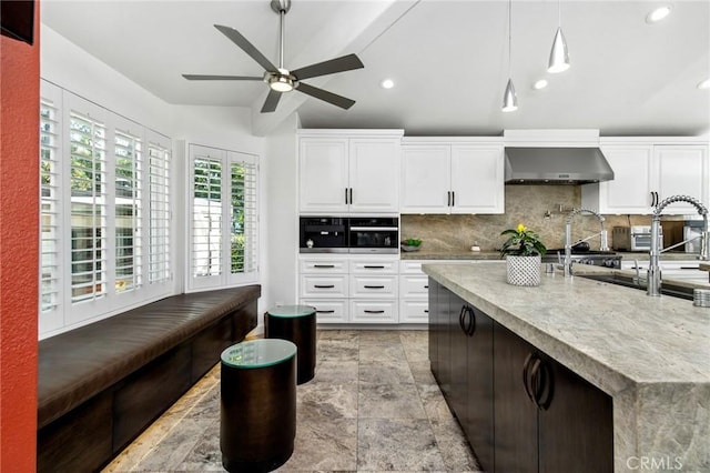 kitchen with wall chimney exhaust hood, pendant lighting, oven, decorative backsplash, and white cabinets