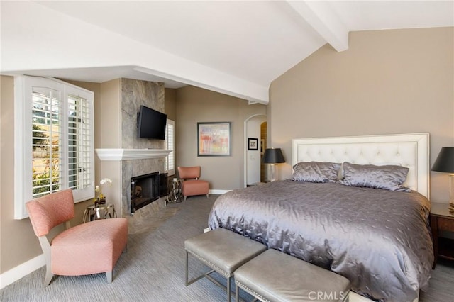 bedroom with carpet flooring, lofted ceiling with beams, and a tile fireplace