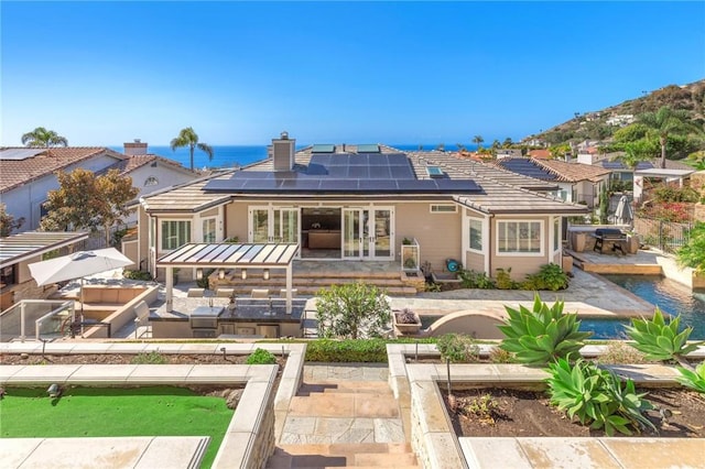 rear view of house with a water view, an outdoor hangout area, a patio area, and french doors