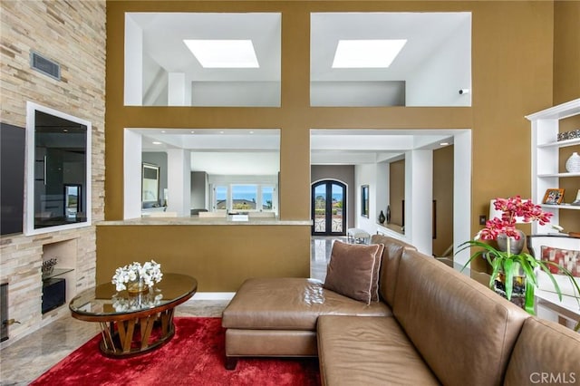 living room with a towering ceiling and a skylight