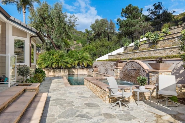 view of patio with a swimming pool with hot tub and pool water feature