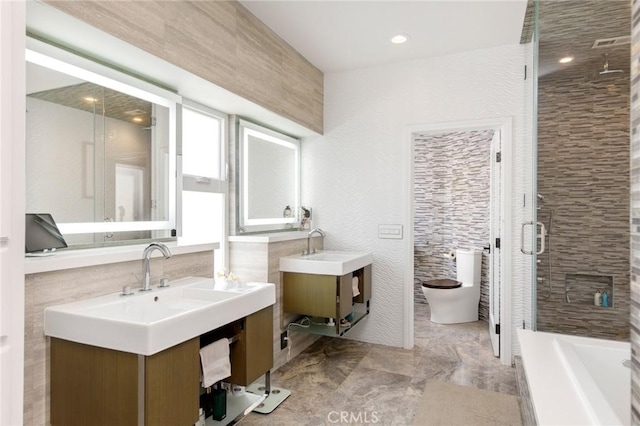 full bathroom featuring vanity, toilet, shower with separate bathtub, and tile walls