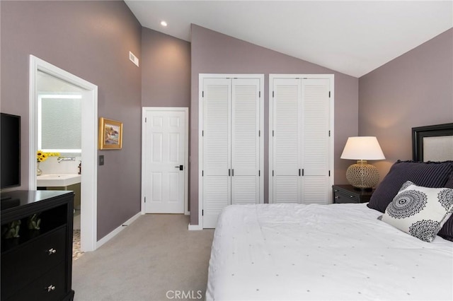 bedroom featuring multiple closets, lofted ceiling, and light colored carpet