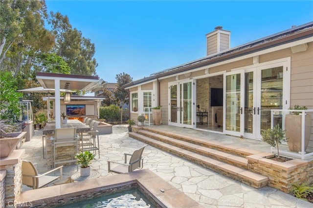 view of patio with french doors and a multi sided fireplace