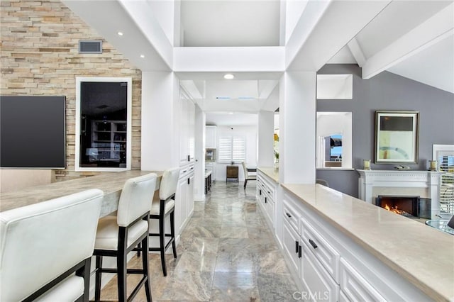 bar featuring white cabinetry and vaulted ceiling with beams