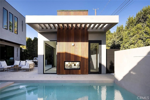 back of property with an outdoor living space and a fenced in pool