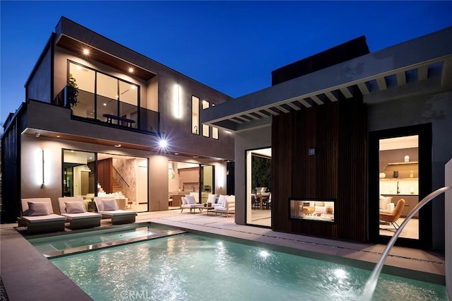 back house at twilight with an outdoor hangout area and a patio