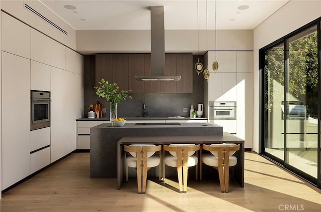 kitchen with dark brown cabinetry, white cabinetry, stainless steel oven, white oven, and backsplash