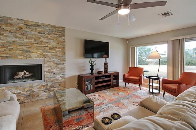 tiled living room with a fireplace and ceiling fan