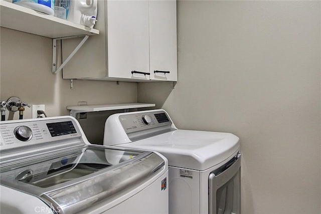 clothes washing area with cabinets and washing machine and clothes dryer