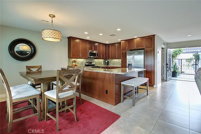 kitchen featuring light stone counters, light tile patterned floors, pendant lighting, stainless steel appliances, and backsplash