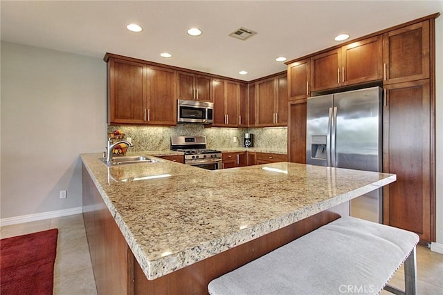 kitchen featuring stainless steel appliances, a breakfast bar, sink, and kitchen peninsula