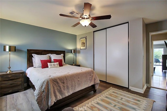 bedroom with dark wood-type flooring, ceiling fan, and a closet