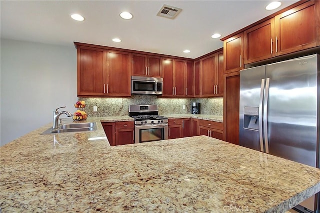 kitchen with tasteful backsplash, sink, stainless steel appliances, and kitchen peninsula