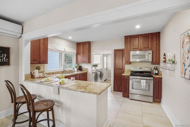 kitchen with stainless steel gas stove, sink, light stone counters, kitchen peninsula, and independent washer and dryer