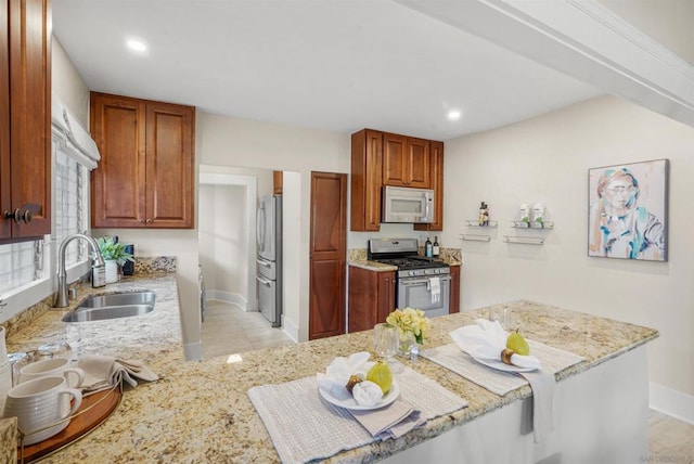 kitchen with light stone counters, sink, stainless steel appliances, and kitchen peninsula