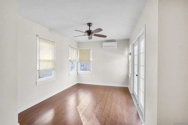 spare room featuring an AC wall unit, dark hardwood / wood-style floors, and ceiling fan