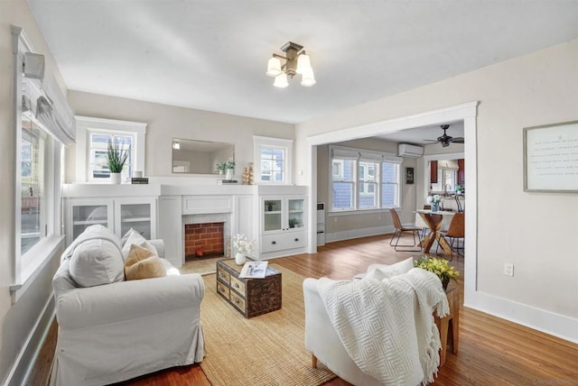 living room featuring an inviting chandelier, a wall mounted air conditioner, and hardwood / wood-style flooring