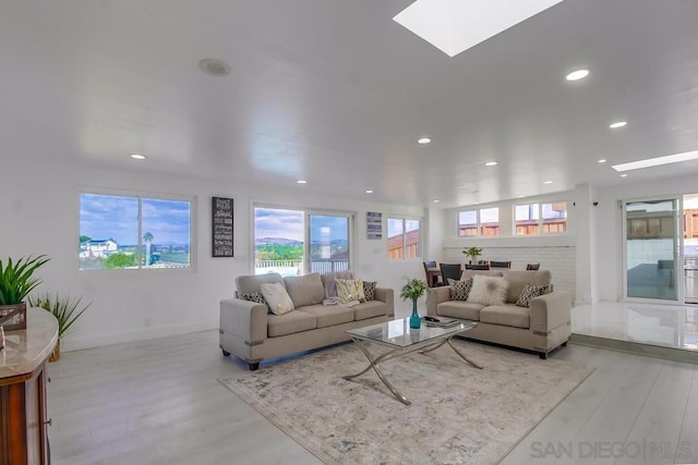 living room featuring light wood-type flooring and a skylight