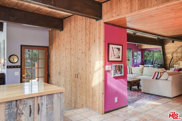 kitchen featuring wood ceiling, plenty of natural light, beam ceiling, and wood walls