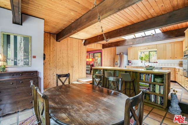 tiled dining room featuring wood ceiling, wooden walls, a skylight, and beam ceiling