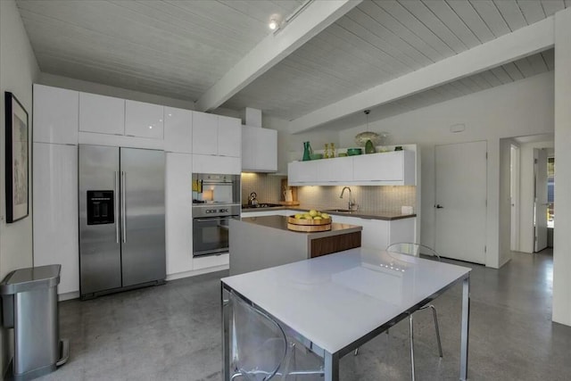 kitchen featuring built in refrigerator, concrete flooring, a center island, and white cabinets