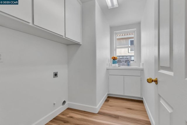 clothes washing area with cabinets, hookup for an electric dryer, and light hardwood / wood-style floors