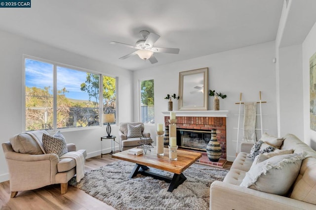 living room with a fireplace, ceiling fan, and light wood-type flooring