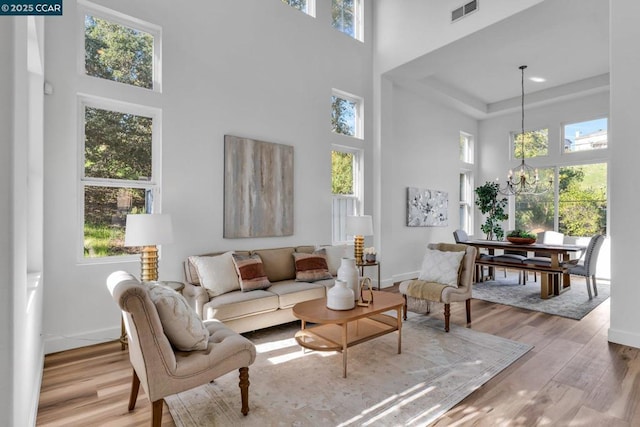 living room featuring a towering ceiling, plenty of natural light, and light hardwood / wood-style floors