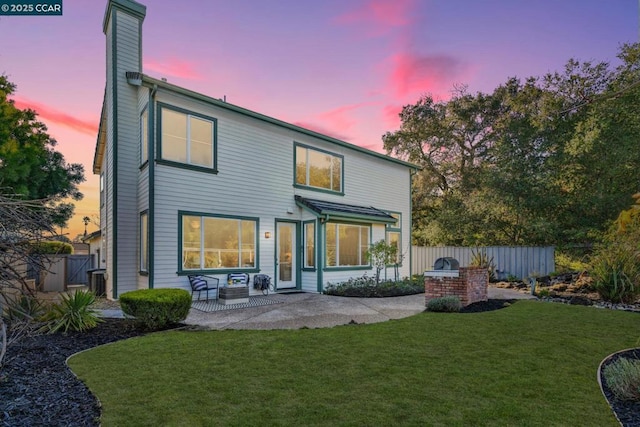 back house at dusk featuring a yard, central AC unit, and a patio area