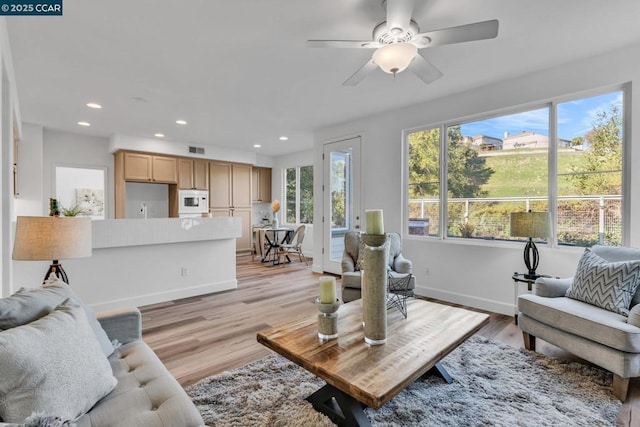 living room with ceiling fan, a wealth of natural light, and light hardwood / wood-style floors