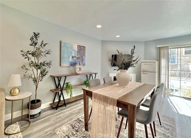 dining space featuring a textured ceiling and light wood-type flooring