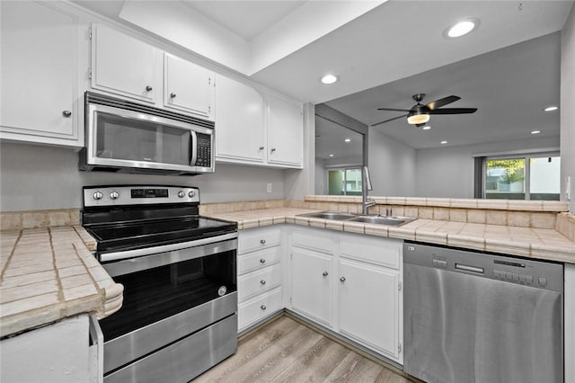 kitchen with white cabinetry, appliances with stainless steel finishes, sink, and tile counters