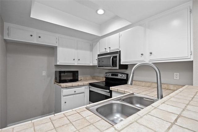 kitchen with white cabinetry, stainless steel appliances, tile countertops, and sink