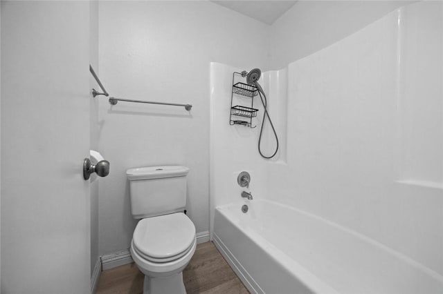 bathroom with hardwood / wood-style floors, shower / bathtub combination, and toilet